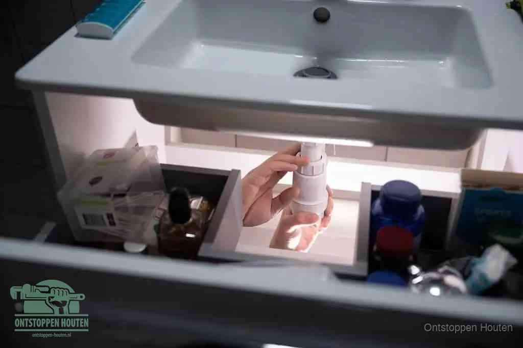 Een pompfles met zeep boven een wastafel, de heet water en afwasmiddel-methode om een vetprop in de afvoer los te maken in Houten