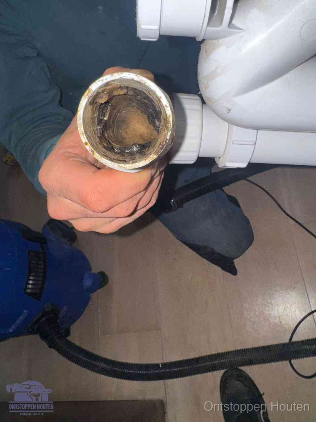 Een losgekoppelde afvoerbuis die van binnen volledig is dichtgeslibd met vet en aanslag, de meest voorkomende oorzaak van een verstopte gootsteen in Houten