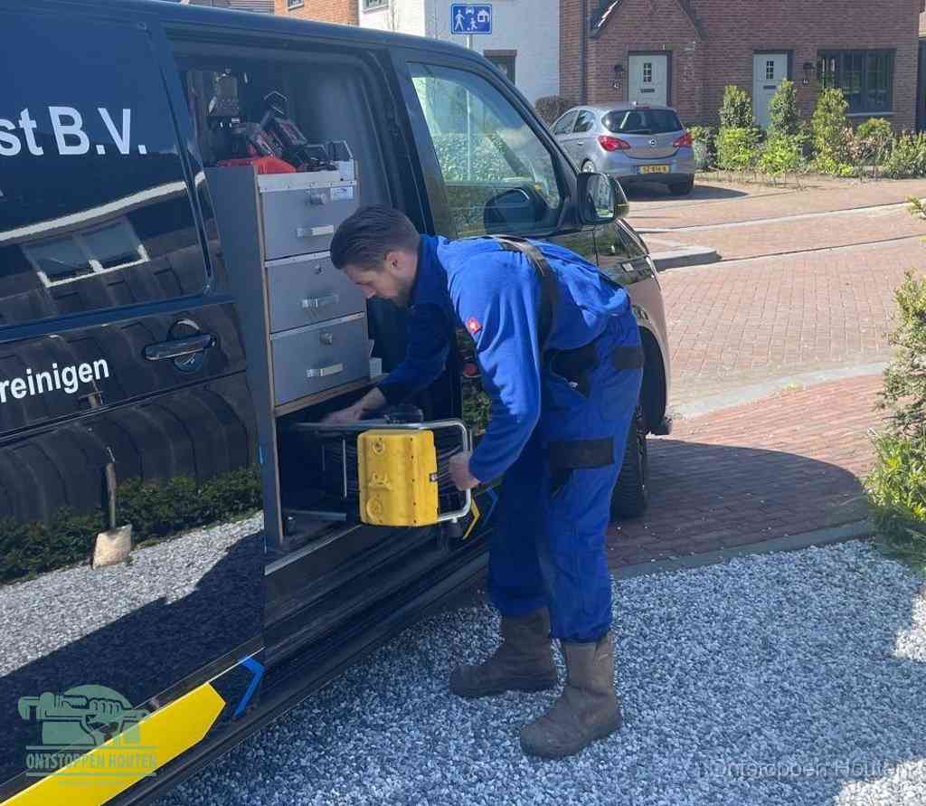 Een monteur pakt buiten op de oprit gereedschap uit de bedrijfsbus, het moment om een professional in te schakelen voor een verstopte afvoer in Houten