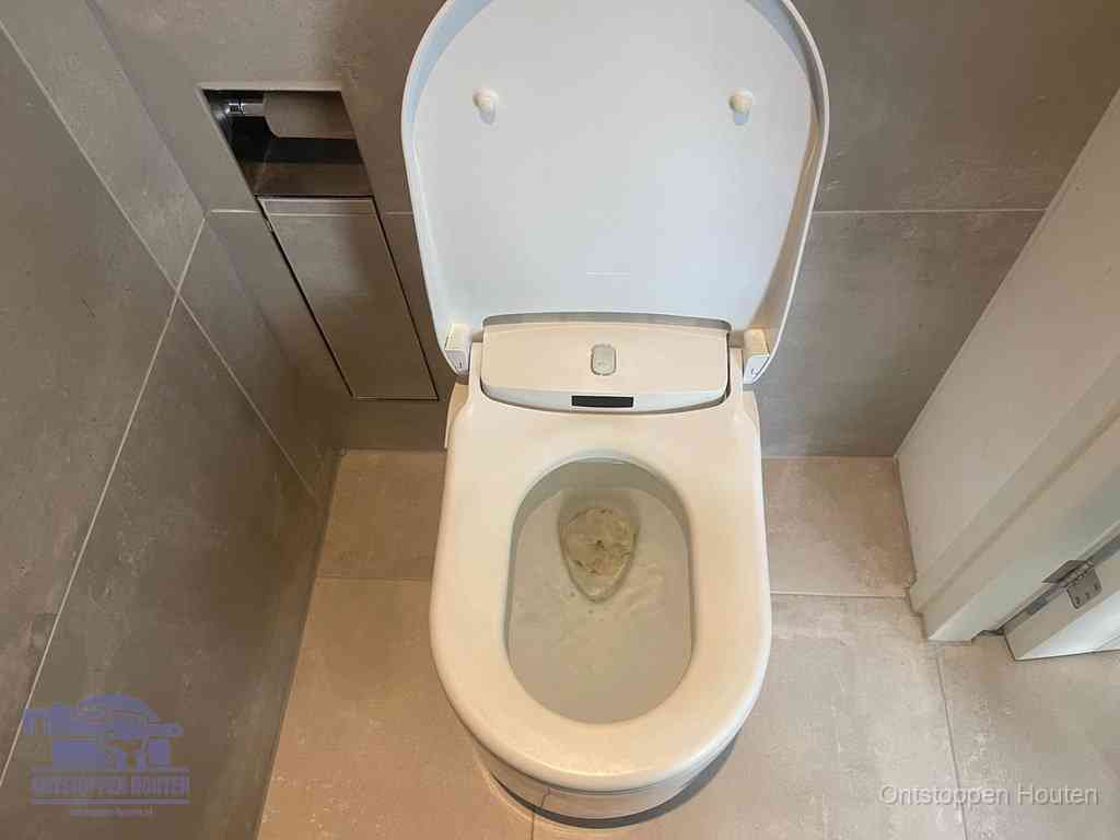 Een wit hangtoilet waarin een prop wc-papier op het water blijft drijven, een duidelijk signaal van een verstopte wc in Houten