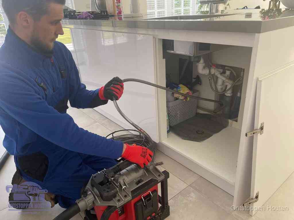 Een monteur reinigt de keukenafvoer grondig met een veermachine om terugkerende gootsteenverstoppingen te voorkomen in Houten