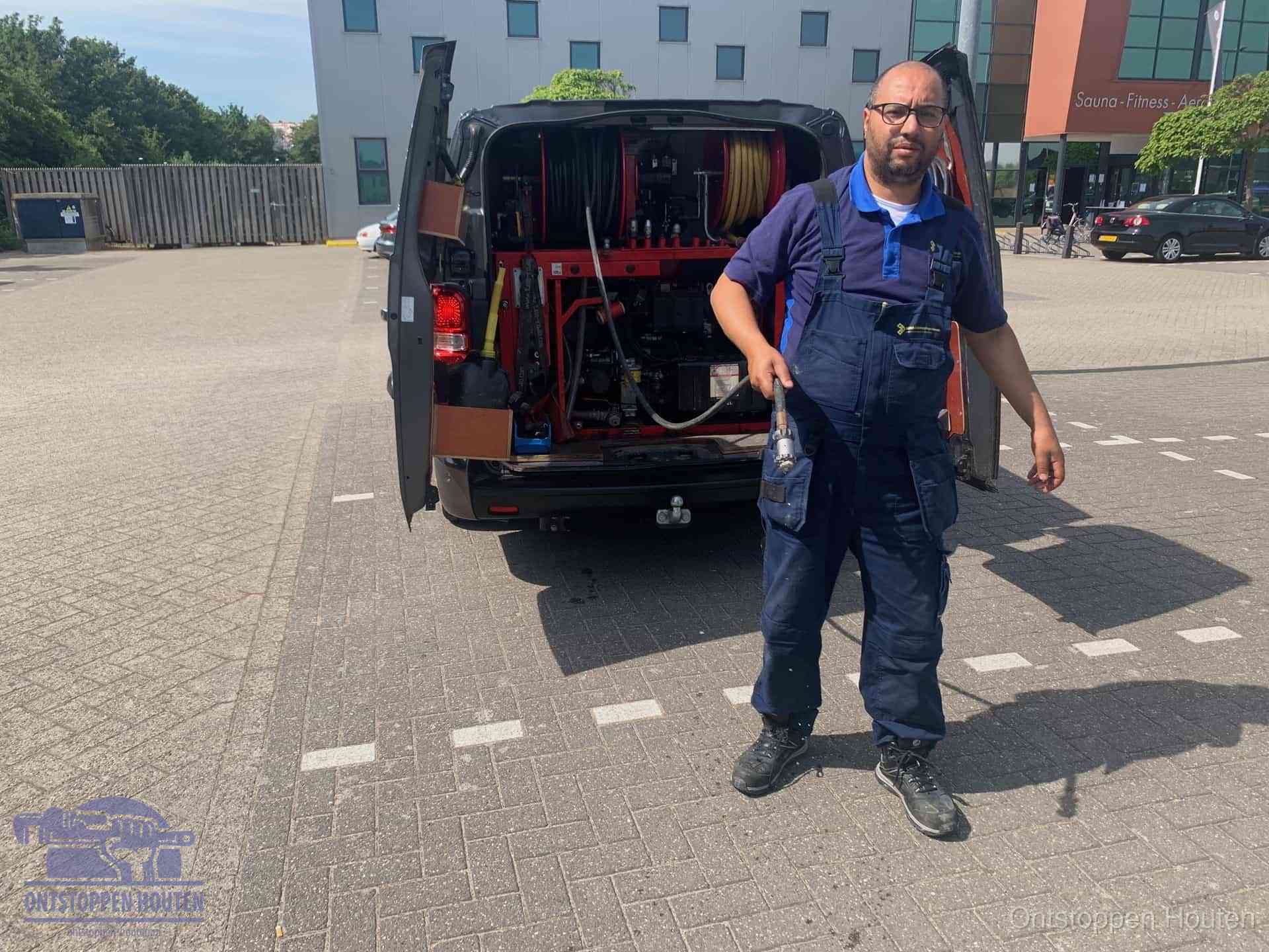 Een monteur bij zijn bestelbus met een hogedruk- en rioolreinigingsunit, klaar om de oorzaak van terugkerende wc-verstoppingen aan te pakken in Houten