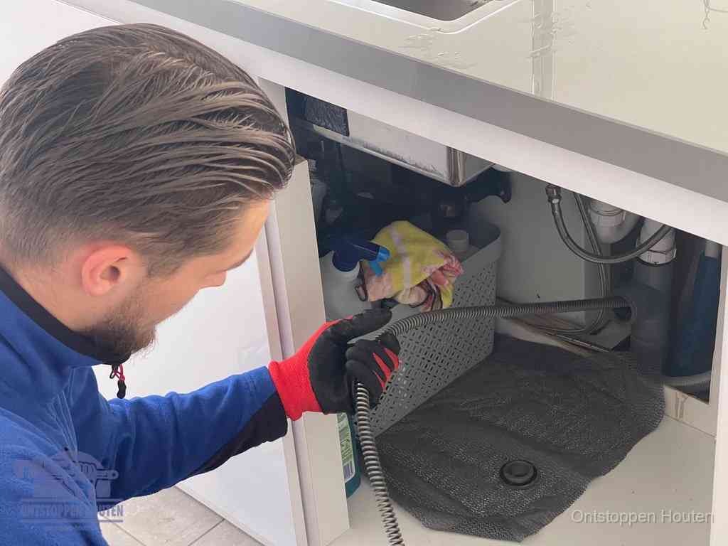 Een monteur voert een flexibele ontstoppingsveer in de afvoer om een verstopping voorbij de bocht van het toilet te bereiken in Houten
