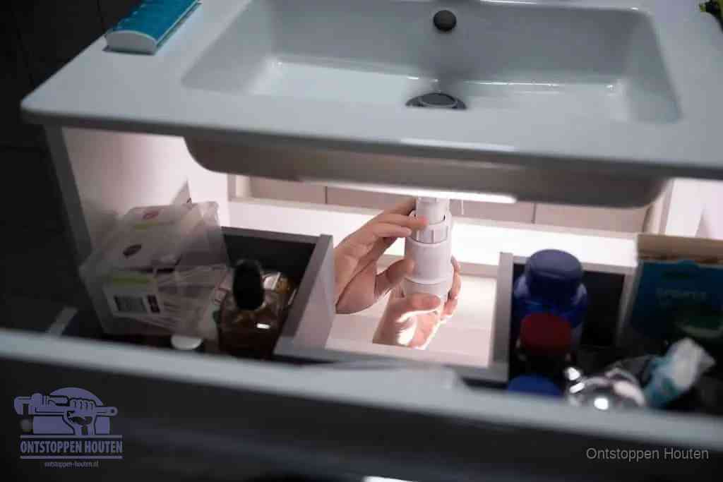 Een pompfles met zeep boven een wastafel in de toiletruimte, de warm water en afwasmiddel-methode om de wc te ontstoppen in Houten