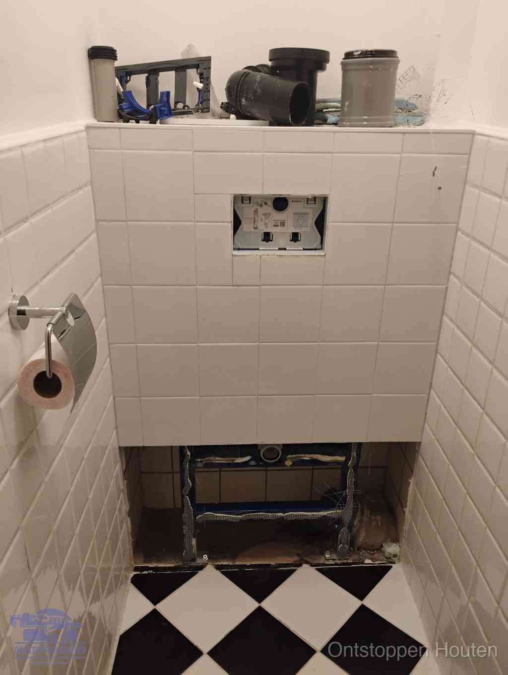 Een toiletruimte waar het hangtoilet en de inbouwreservoir-onderdelen zijn vrijgelegd voor onderhoud, periodiek nazicht voorkomt een wc-verstopping in Houten