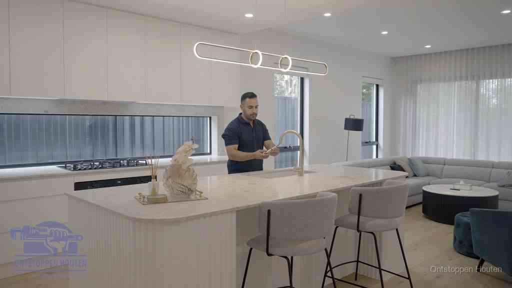 Een bewoner bij de keukenspoelbak die zelf aan de slag gaat met een verstopte gootsteen in Houten